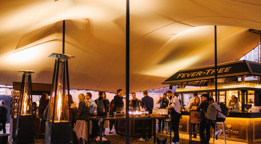 Branded corporate cocktail event hosted under a stretch tent