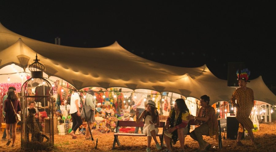 Colourful night-time music festival under a large stretch tent